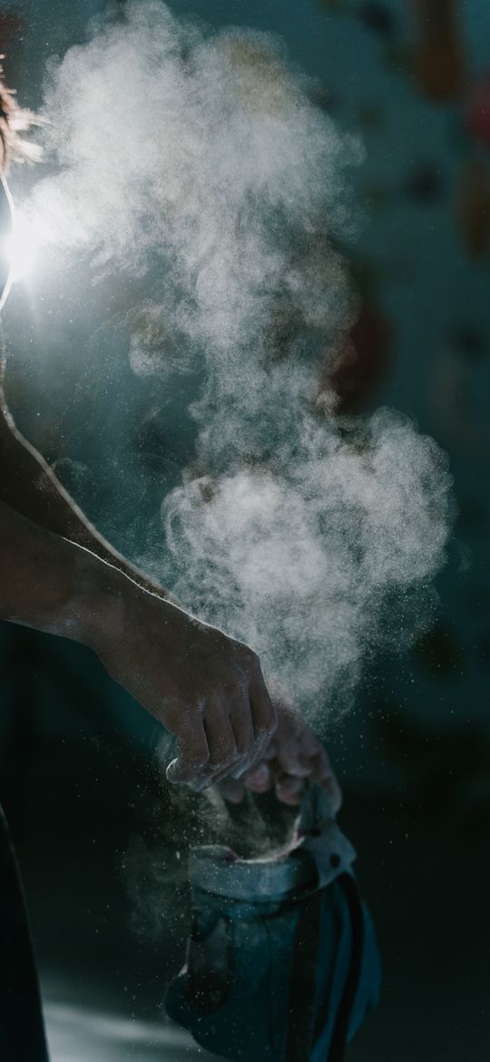 A cloud of chalk as a climber dips into a chalk bag